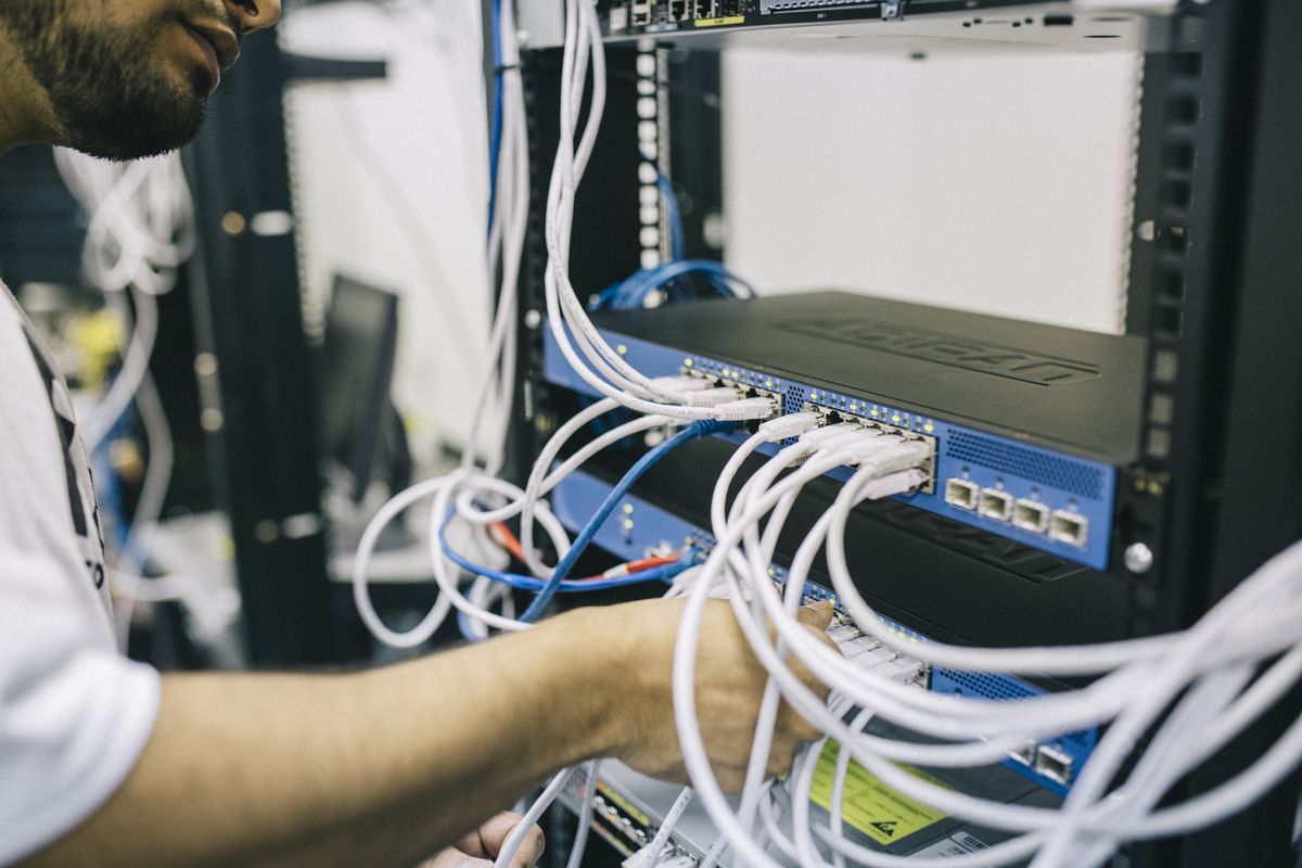 Engineer working on fiber and network equipment in a rack