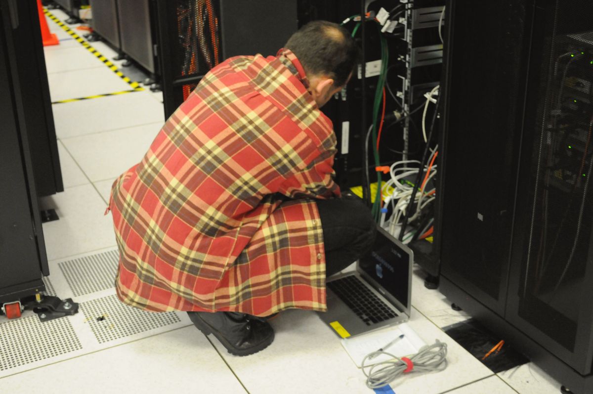 Technician with a laptop working on a server rack in a data center