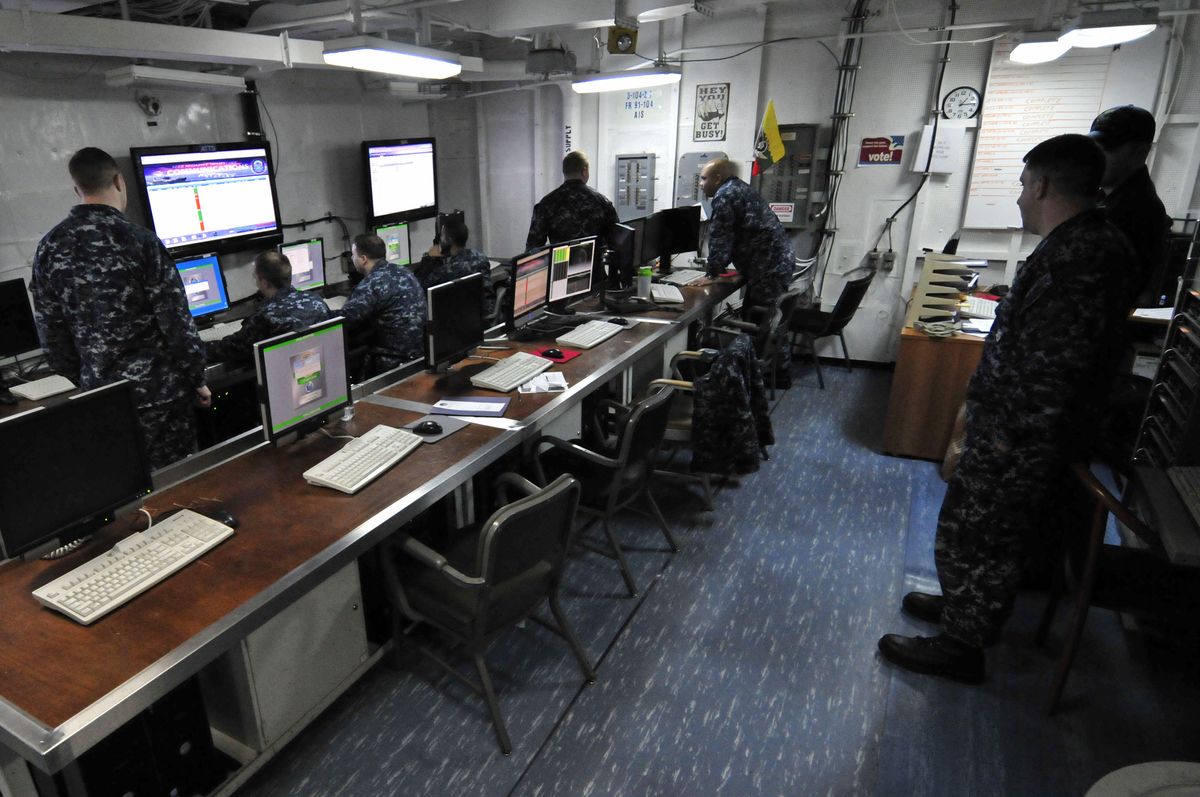 U.S. Navy personnel monitoring network operations aboard a ship